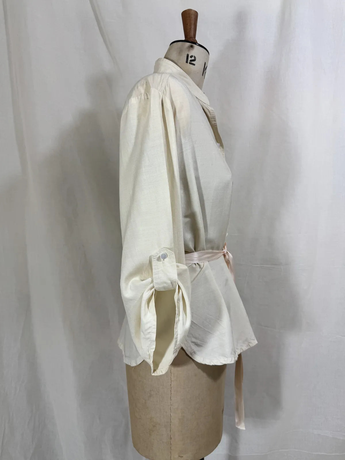 1960 white silk blouse on a mannequin against a white background