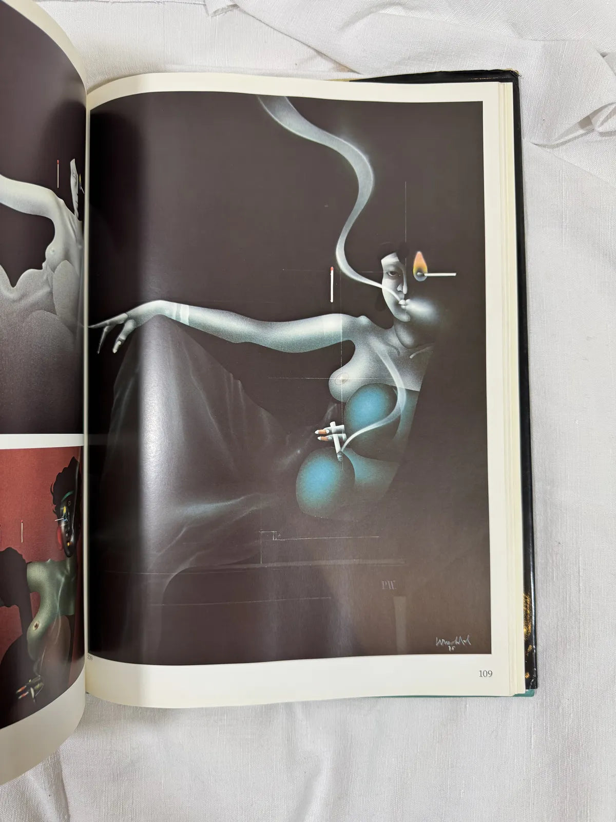 Open book with a black and white illustration of a nude figure holding a cigarette on a white surface.