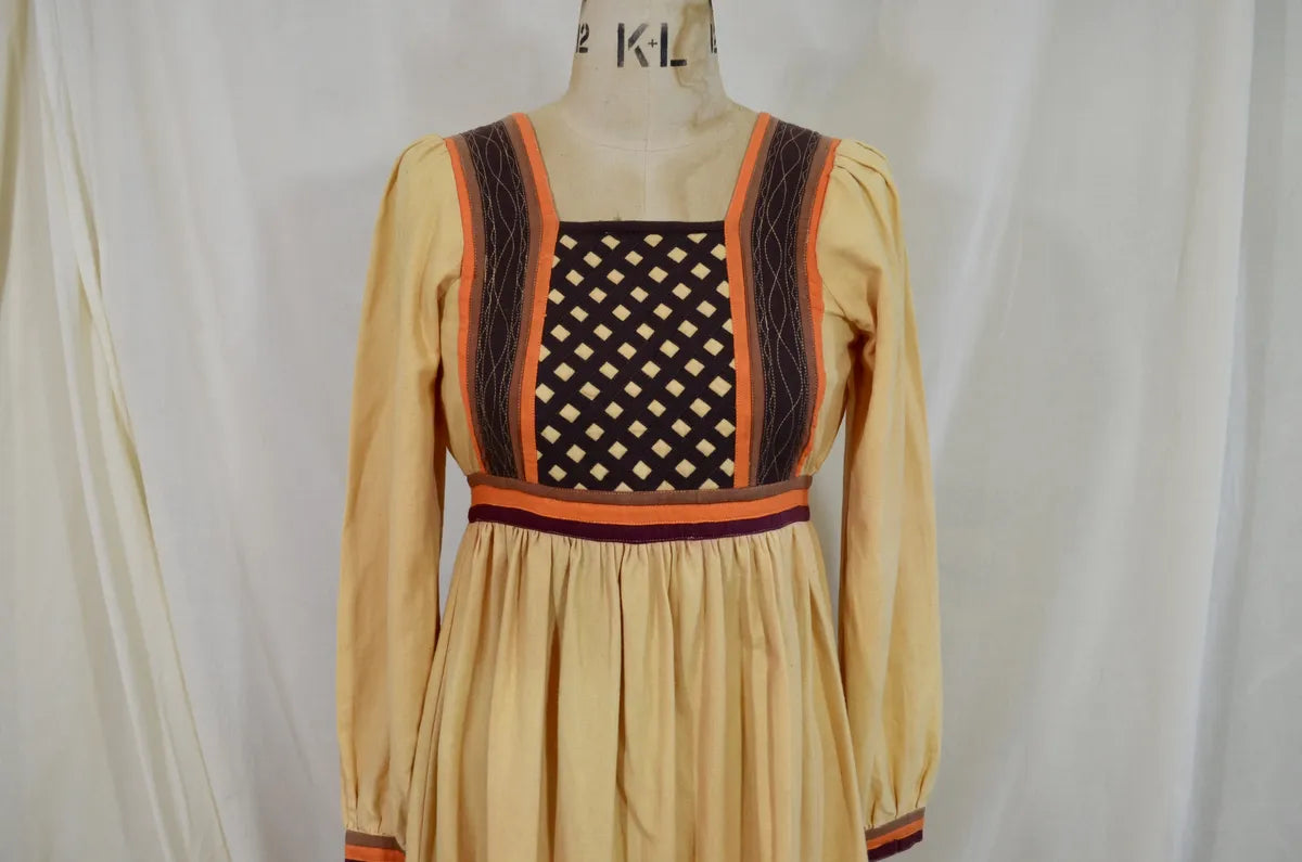 Vintage Indian thick cotton yellow dress with patchwork detail on plain background