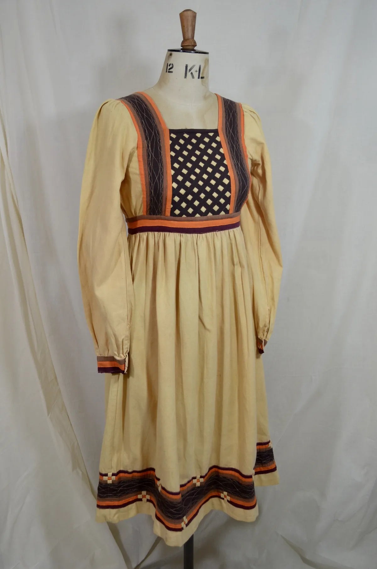 Vintage Indian thick cotton yellow dress with patchwork detail on plain background
