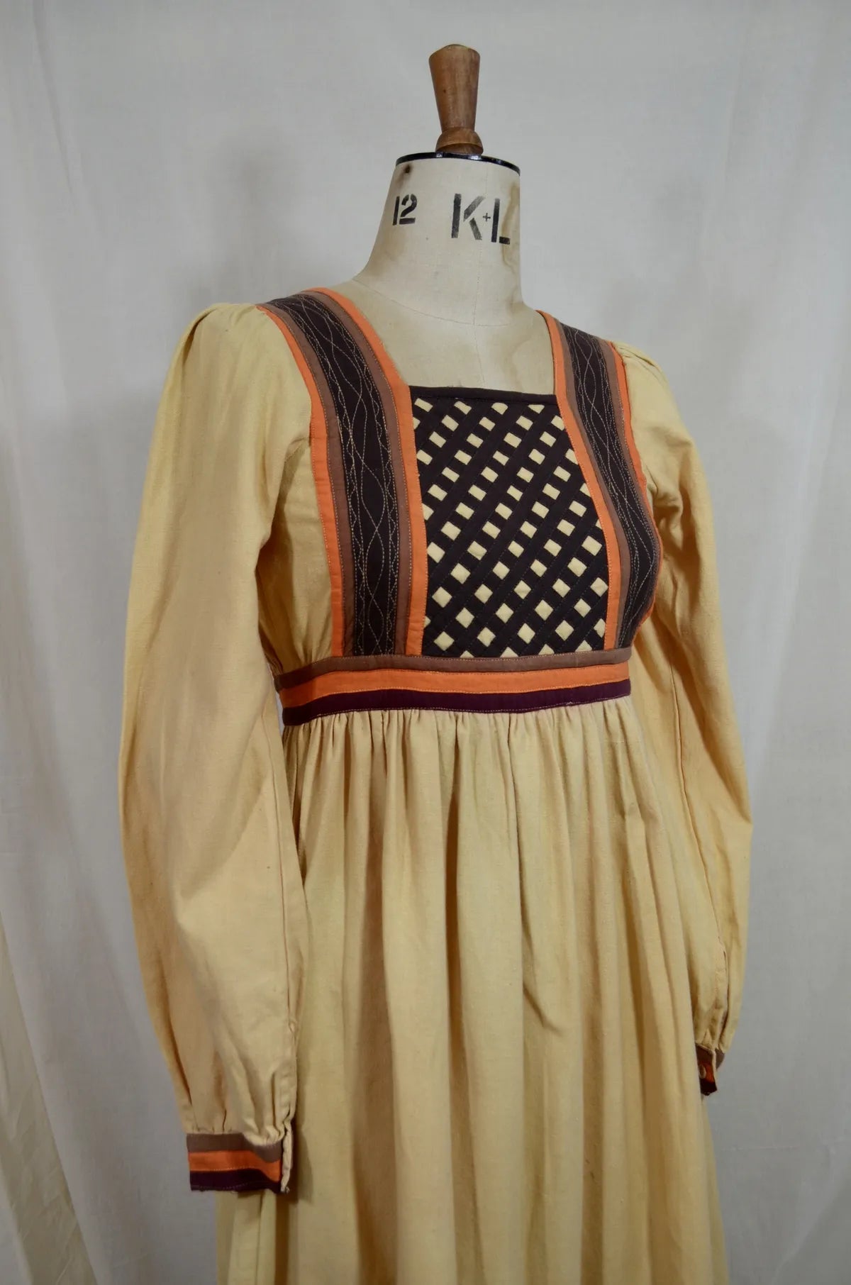 Vintage Indian thick cotton yellow dress with patchwork detail on plain background