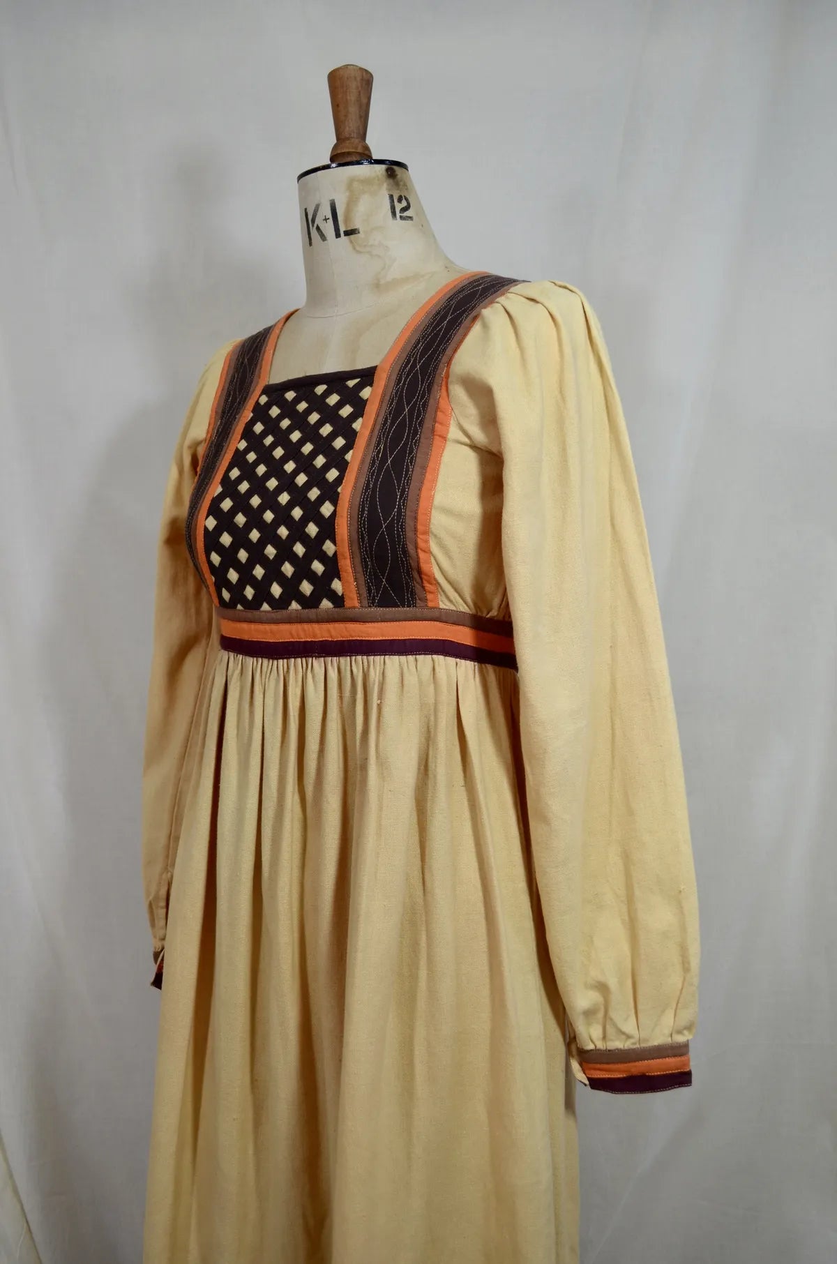 Vintage Indian thick cotton yellow dress with patchwork detail on plain background