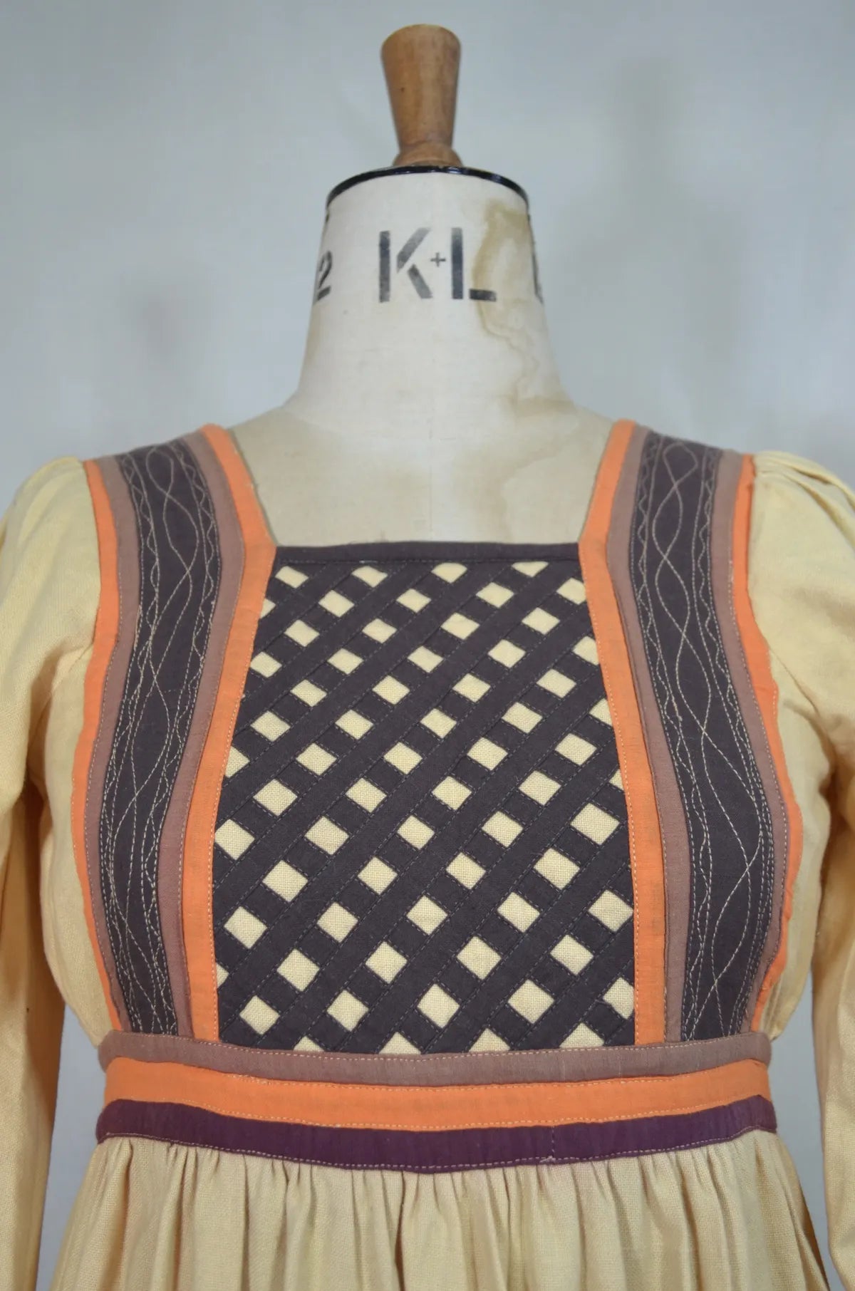 Vintage Indian thick cotton yellow dress with patchwork detail on plain background