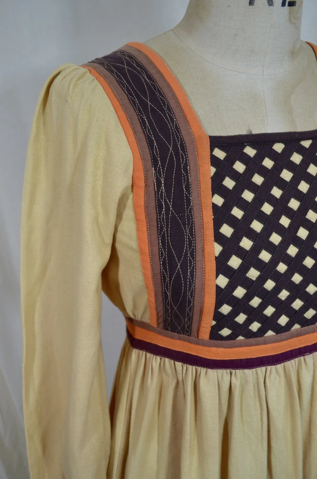 Vintage Indian thick cotton yellow dress with patchwork detail on plain background