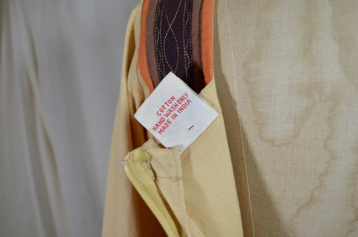 Vintage Indian thick cotton yellow dress with patchwork detail on plain background