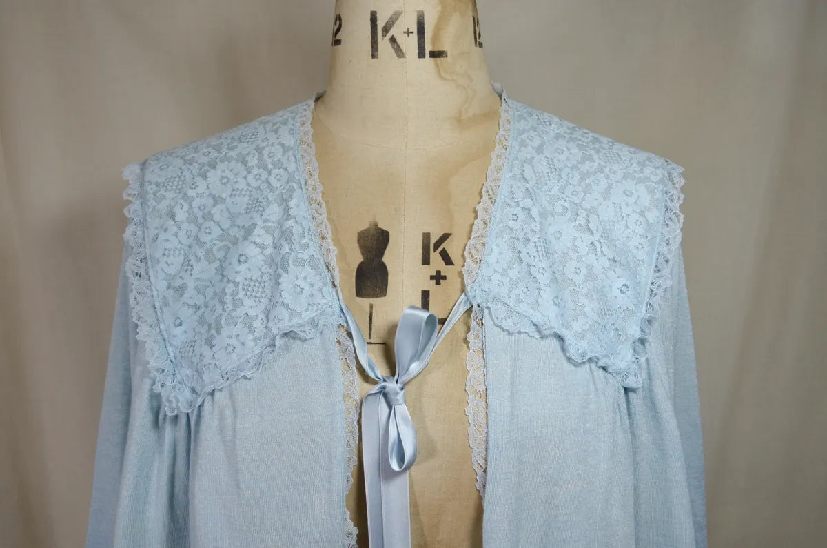 1930s Light blue lace-trimmed wool bed jacket on a mannequin against a beige background
