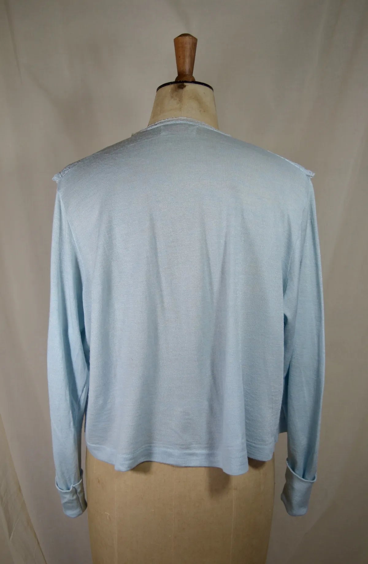 1930s Light blue lace-trimmed wool bed jacket on a mannequin against a beige background