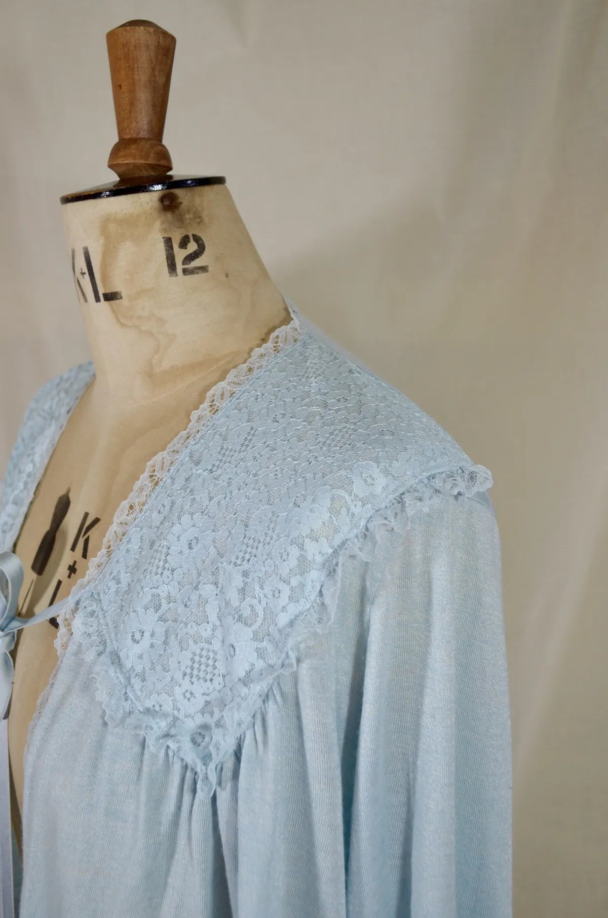 1930s Light blue lace-trimmed wool bed jacket on a mannequin against a beige background