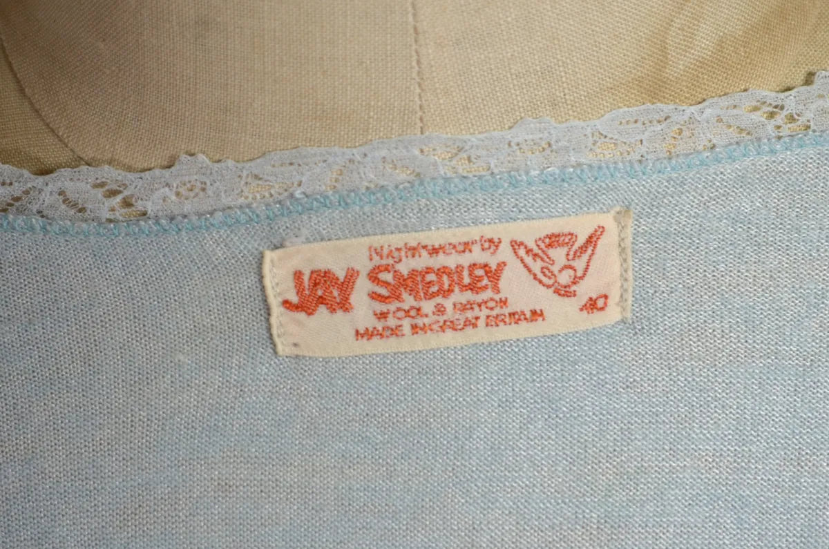 1930s Light blue lace-trimmed wool bed jacket on a mannequin against a beige background