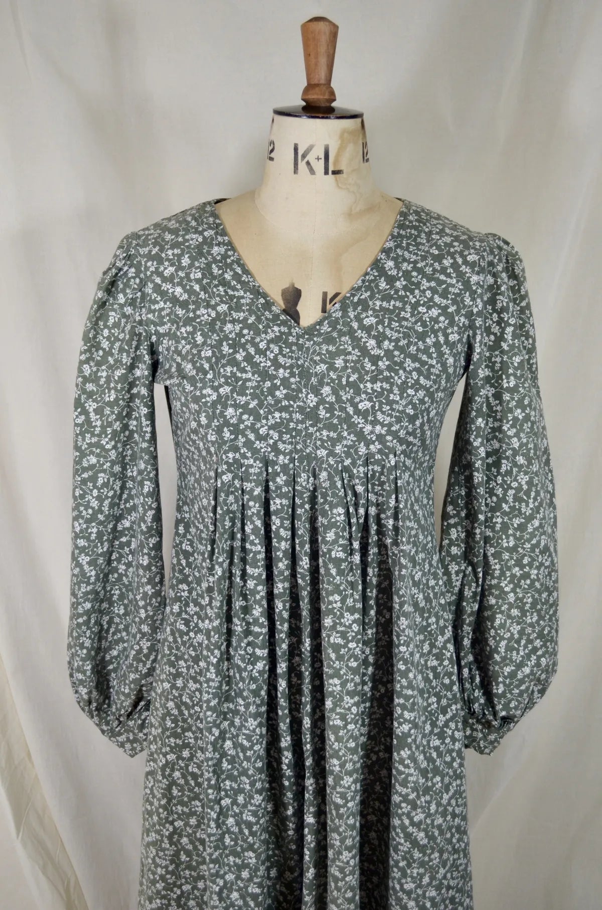 Green floral dress on a mannequin against a white background