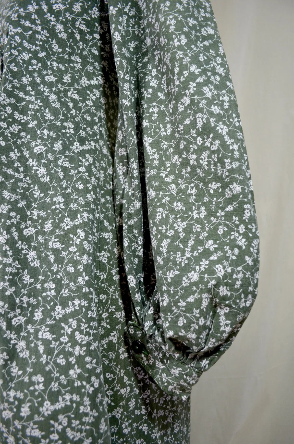Green fabric with white floral pattern on a plain background