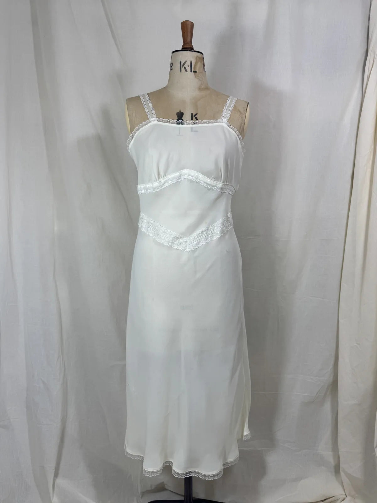 White nightgown on a mannequin against a plain background
