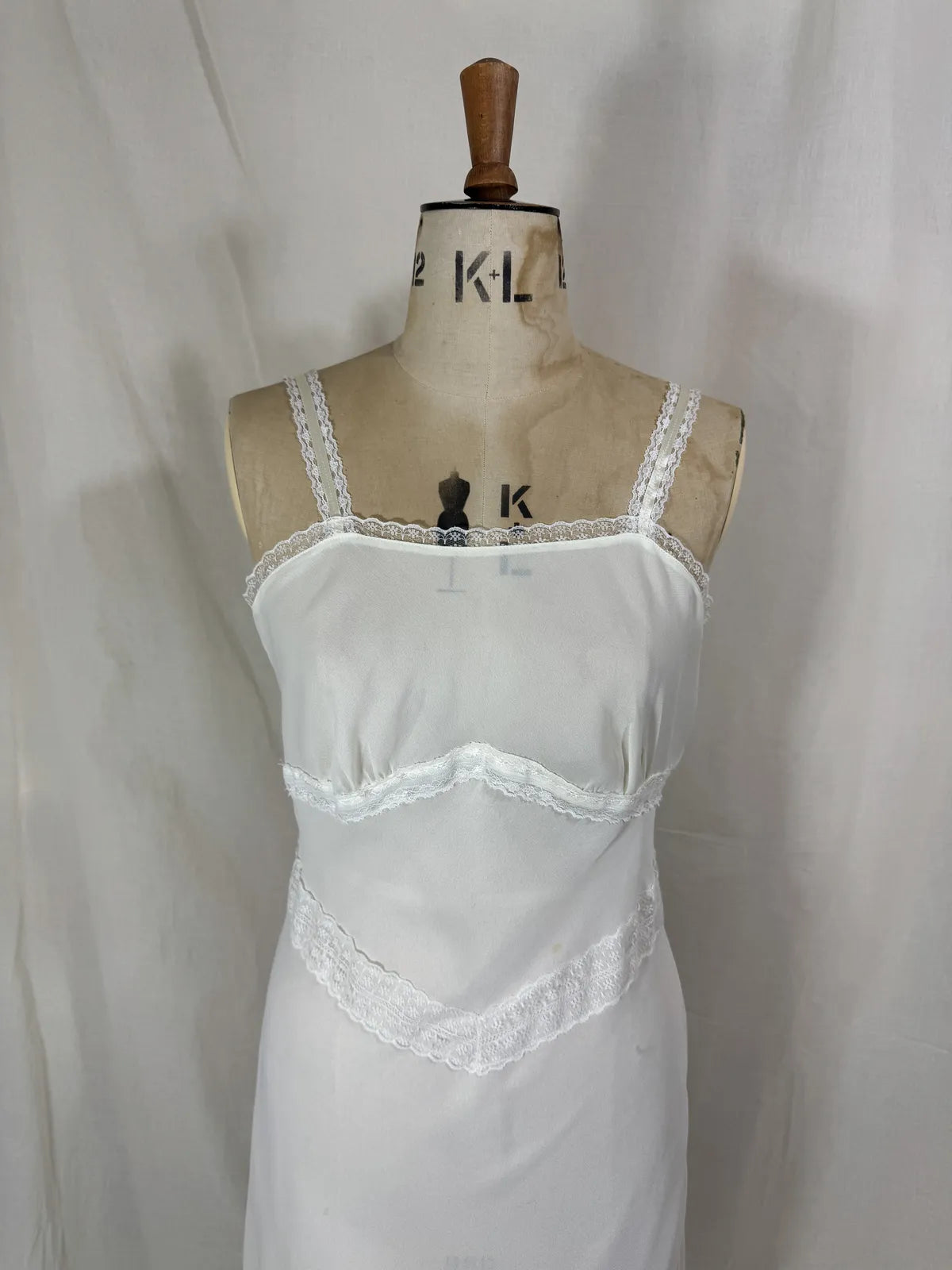 White nightgown on a mannequin against a plain background