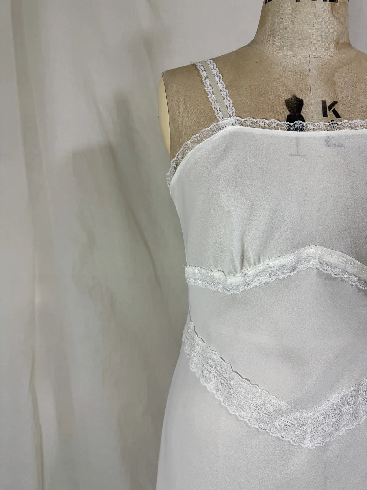 White nightgown on a mannequin against a plain background
