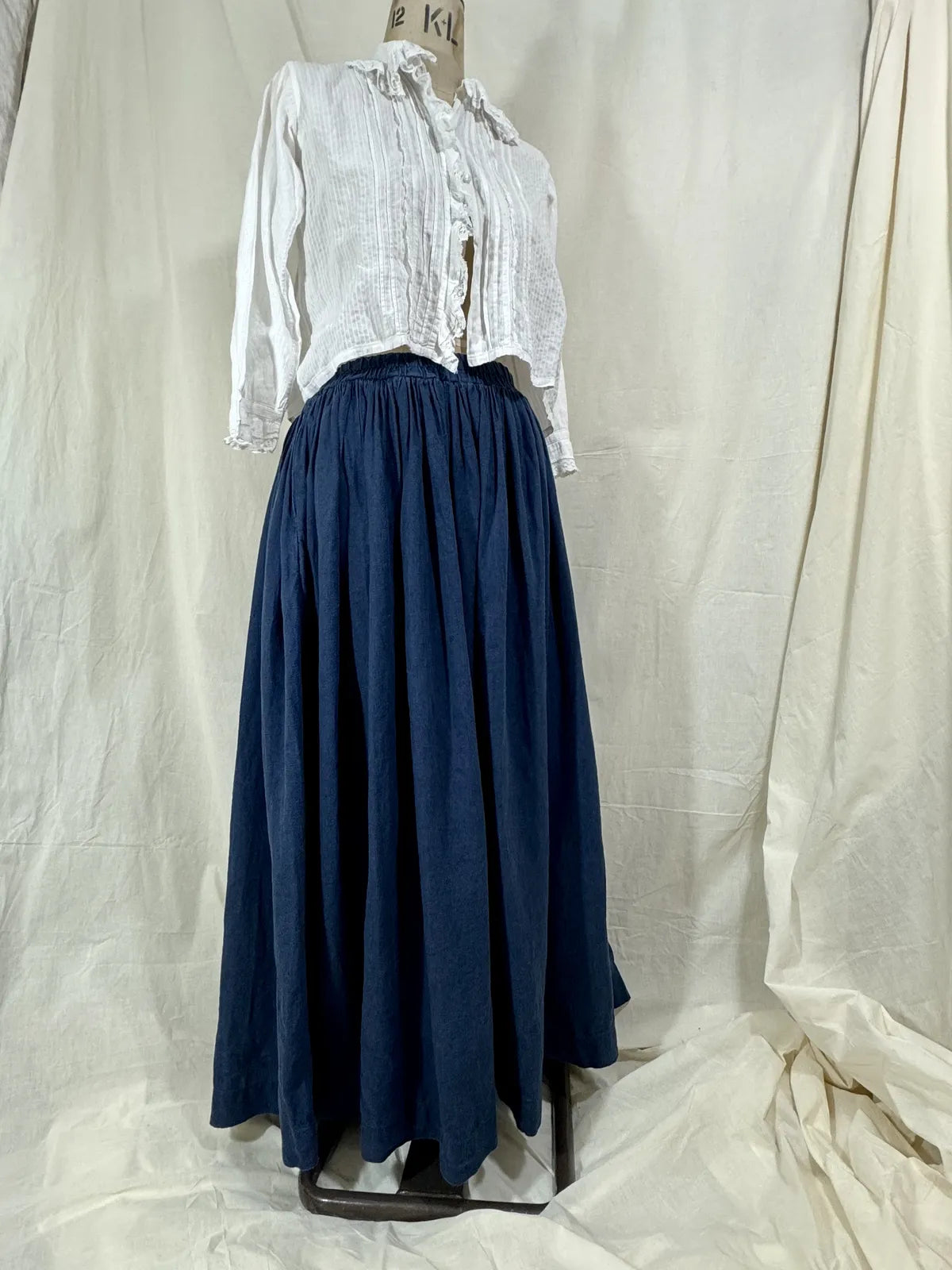 Mannequin wearing a white blouse and navy blue skirt on a white background