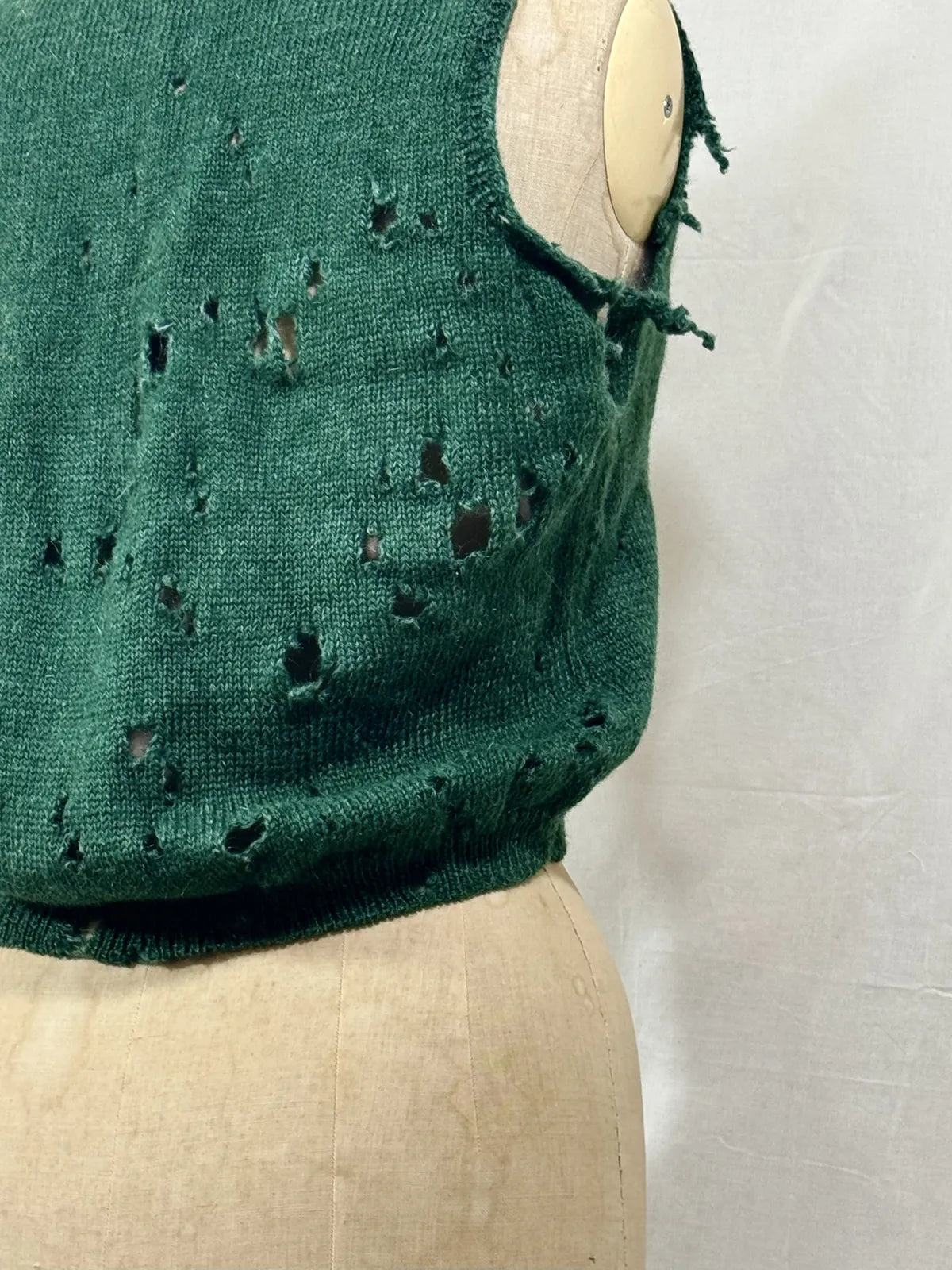 1920s green knitted vest on a mannequin against a white background