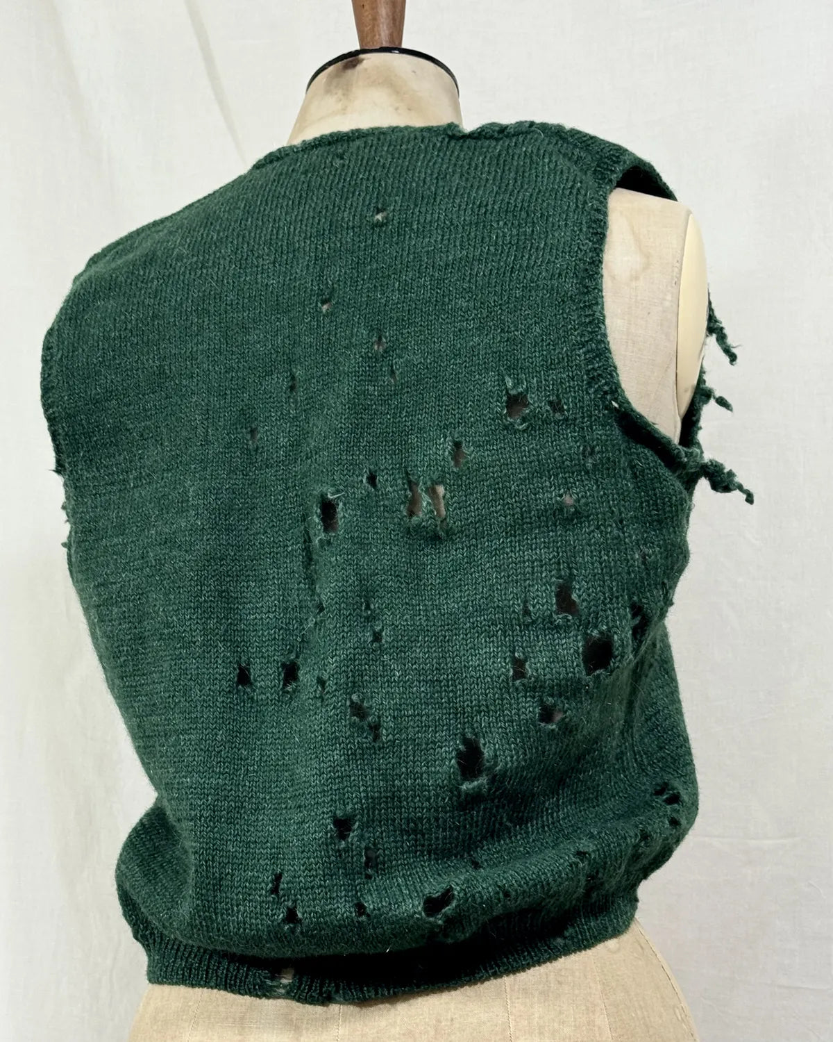 1920s green knitted vest on a mannequin against a white background