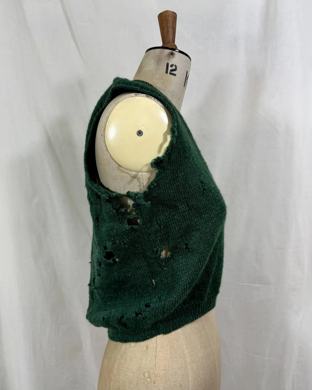 1920s green knitted vest on a mannequin against a white background