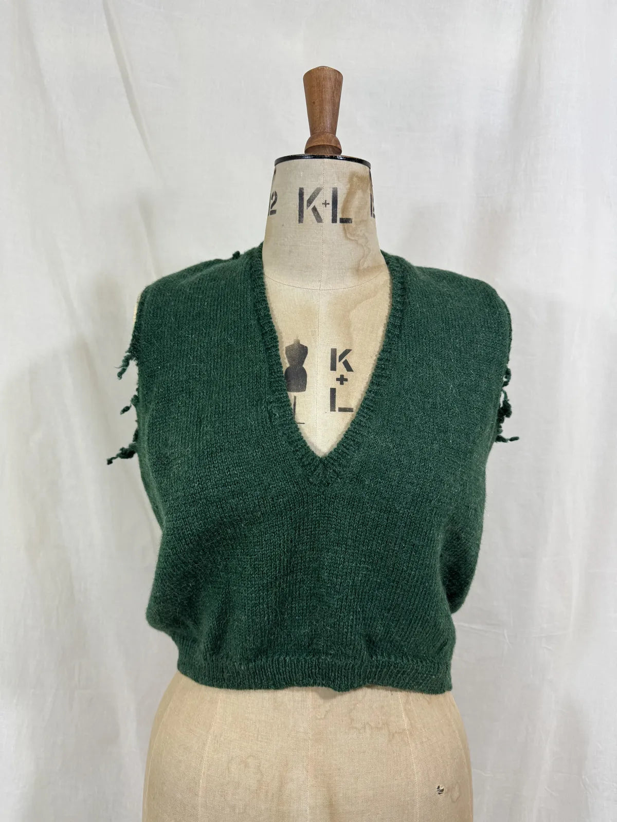 1920s green knitted vest on a mannequin against a white background
