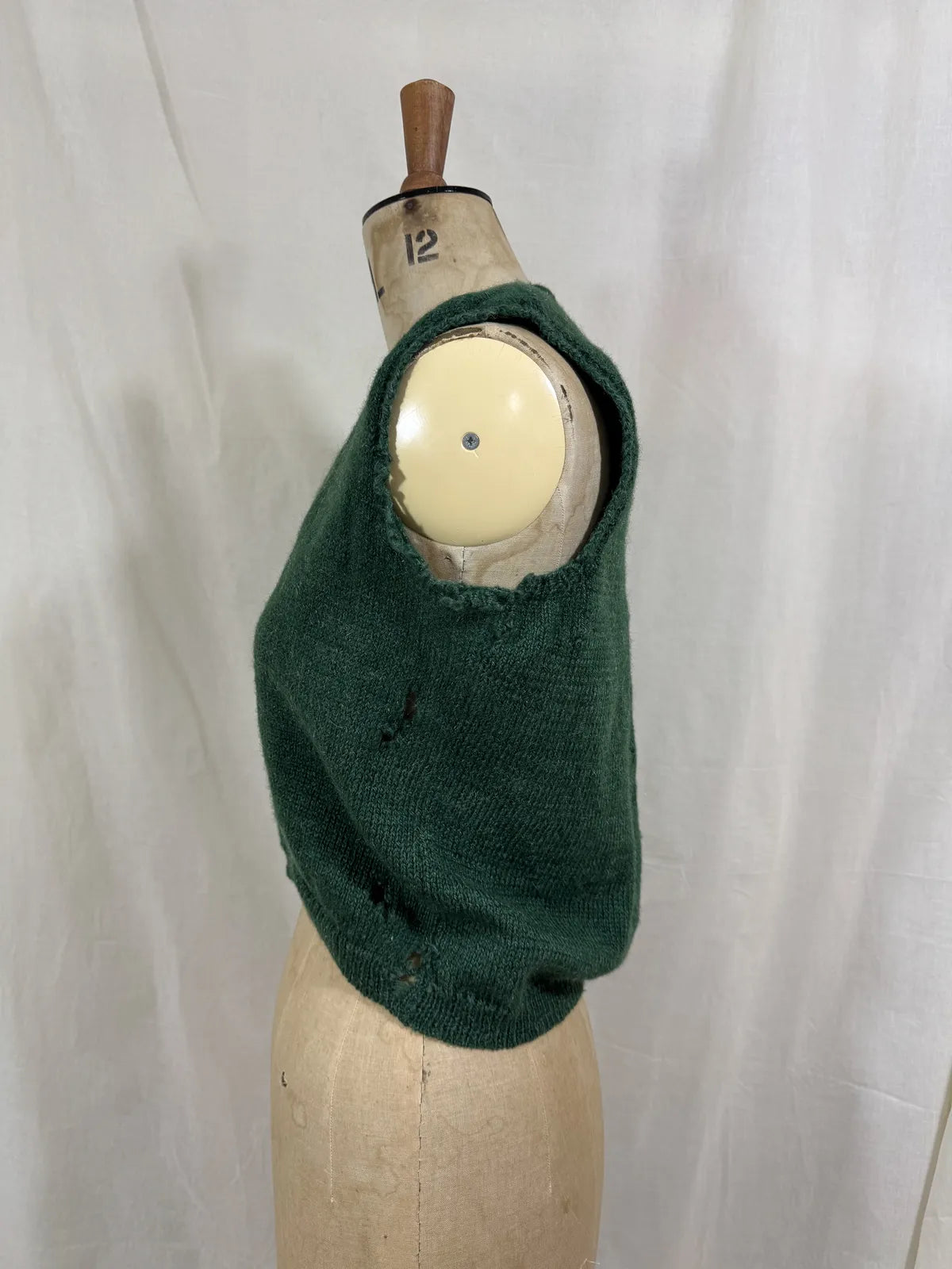 1920s green knitted vest on a mannequin against a white background