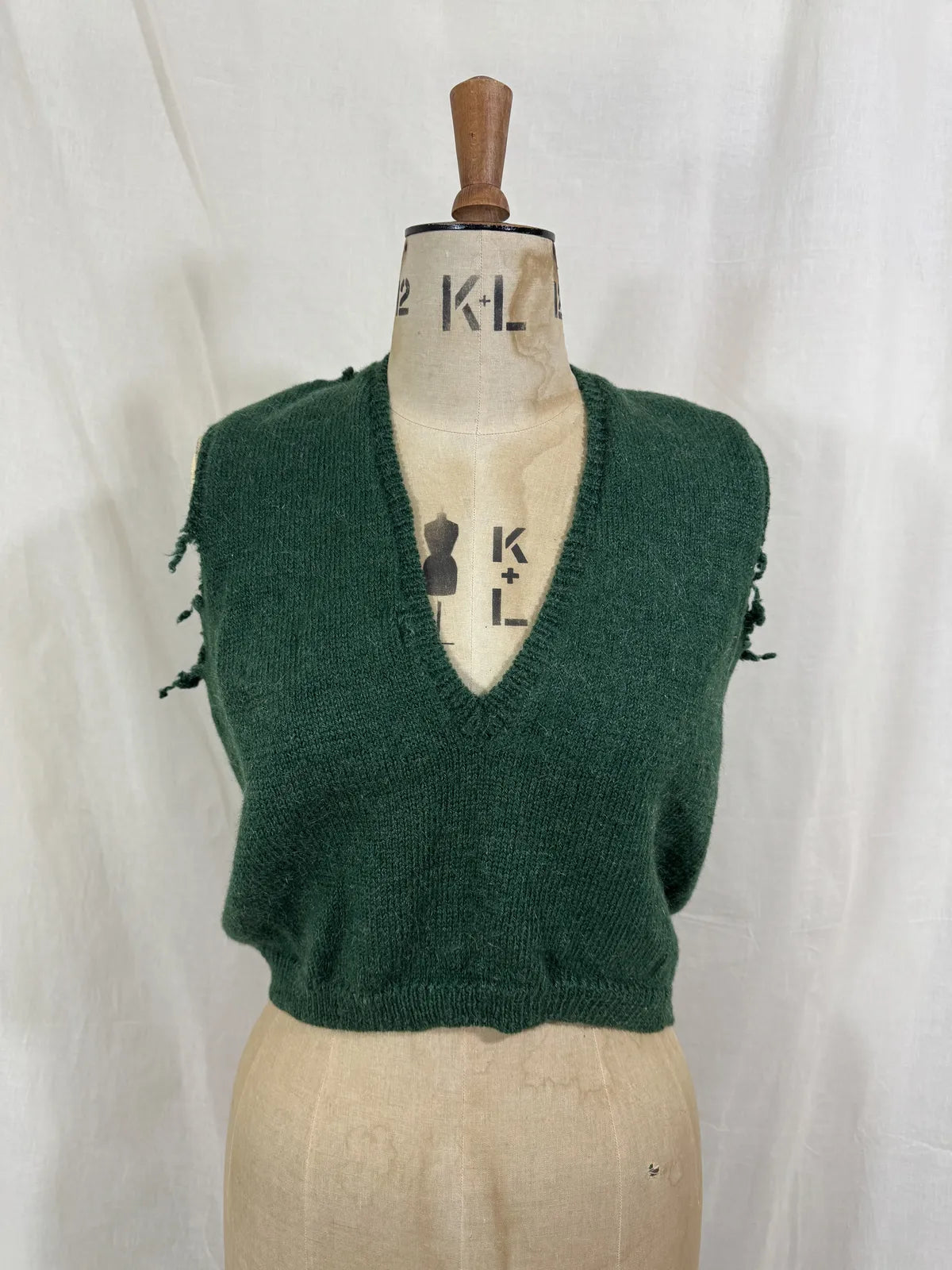 1920s green knitted vest on a mannequin against a white background