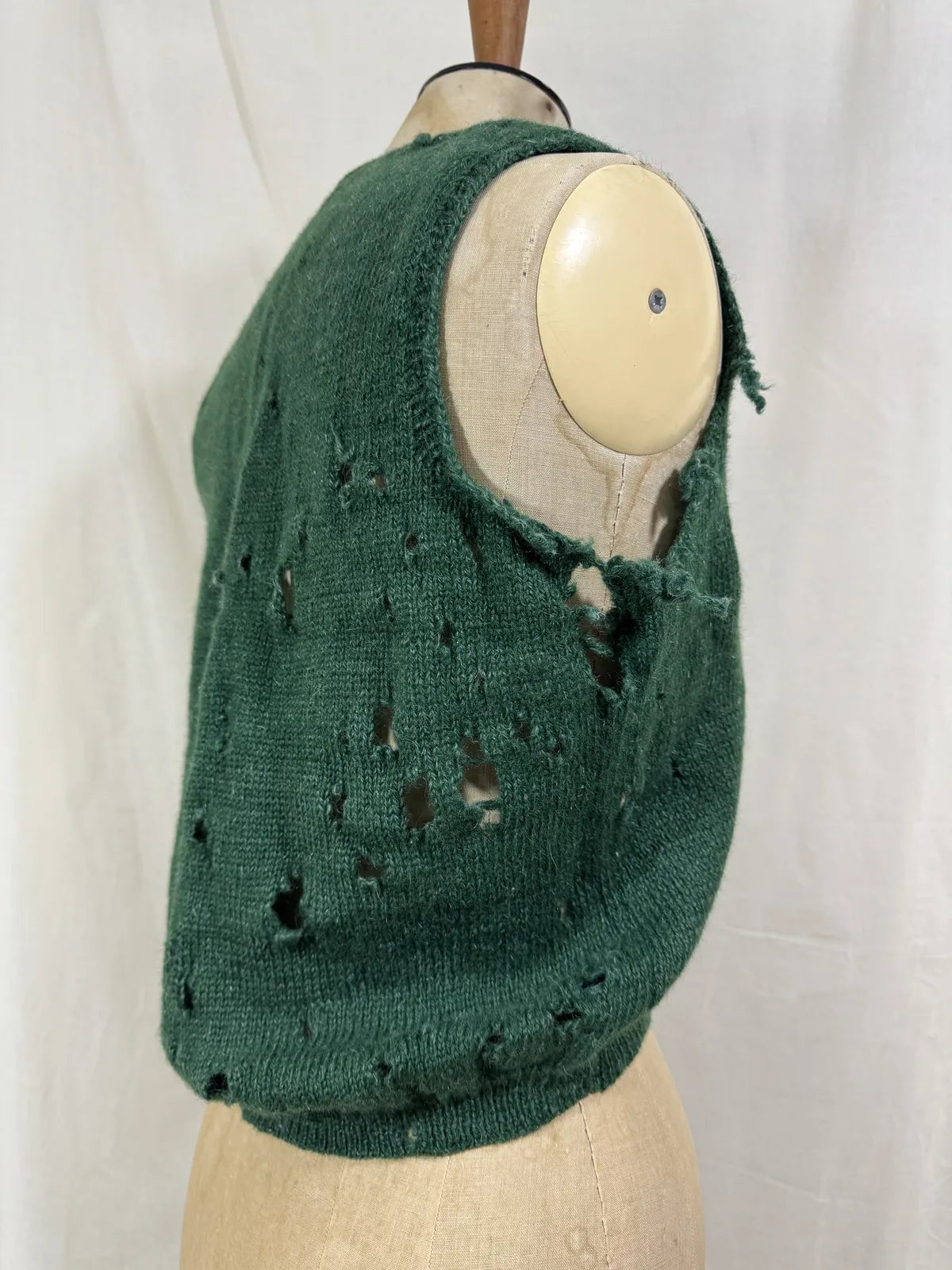 1920s green knitted vest on a mannequin against a white background