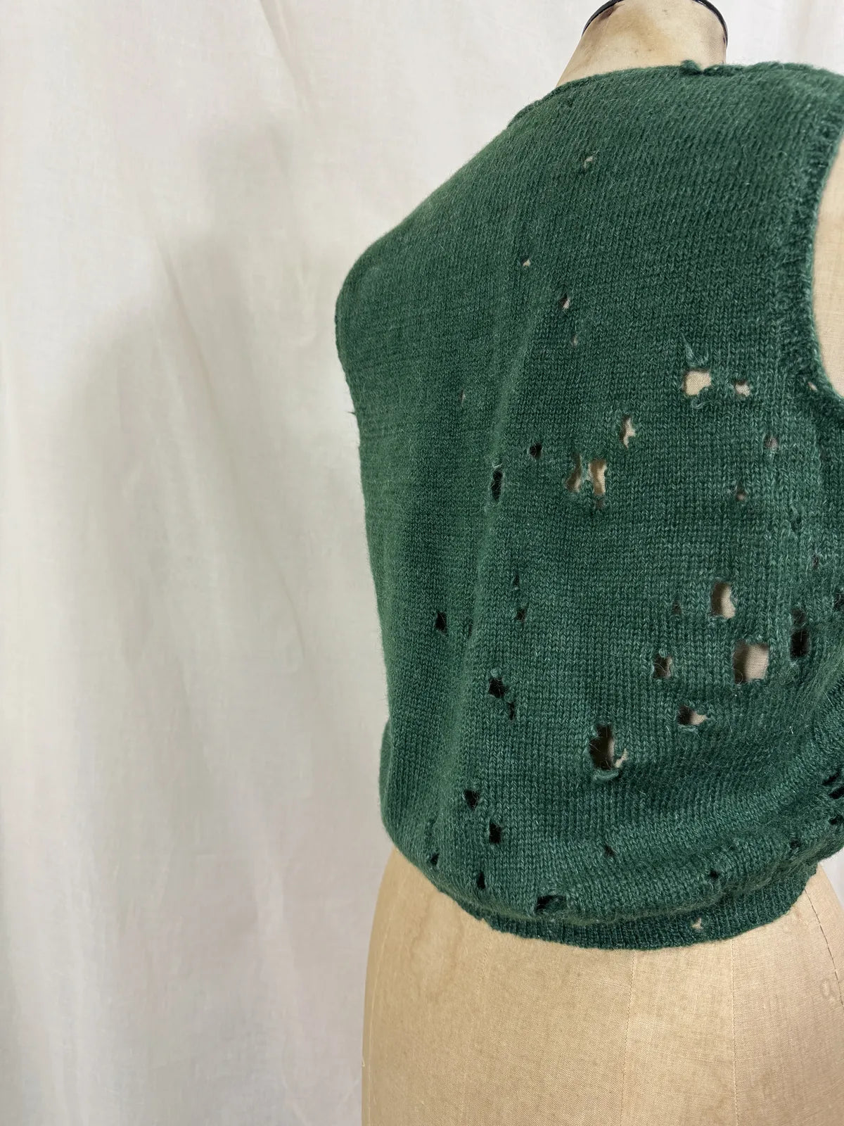 1920s green knitted vest on a mannequin against a white background
