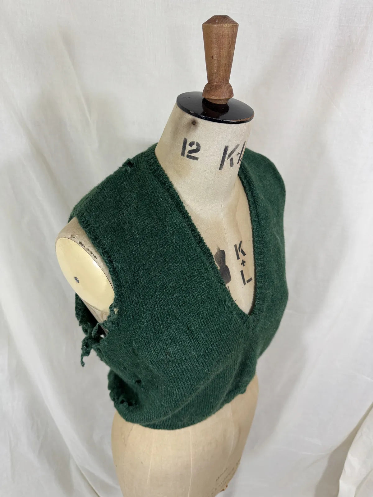 1920s green knitted vest on a mannequin against a white background