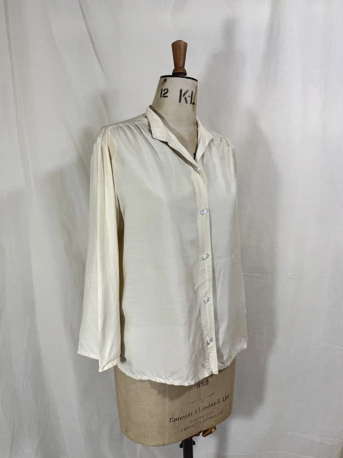 1960 white silk blouse on a mannequin against a white background