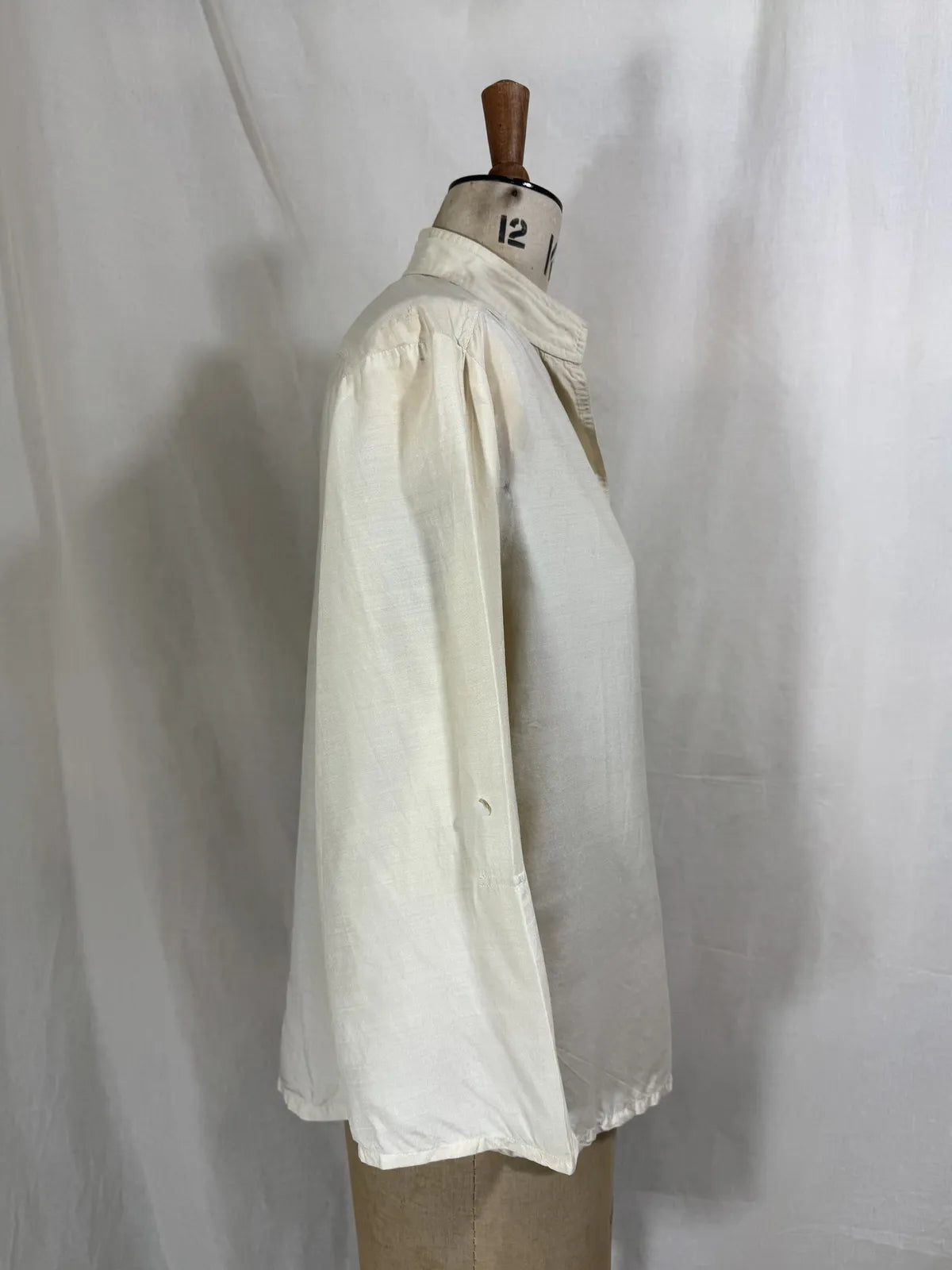 1960 white silk blouse on a mannequin against a white background