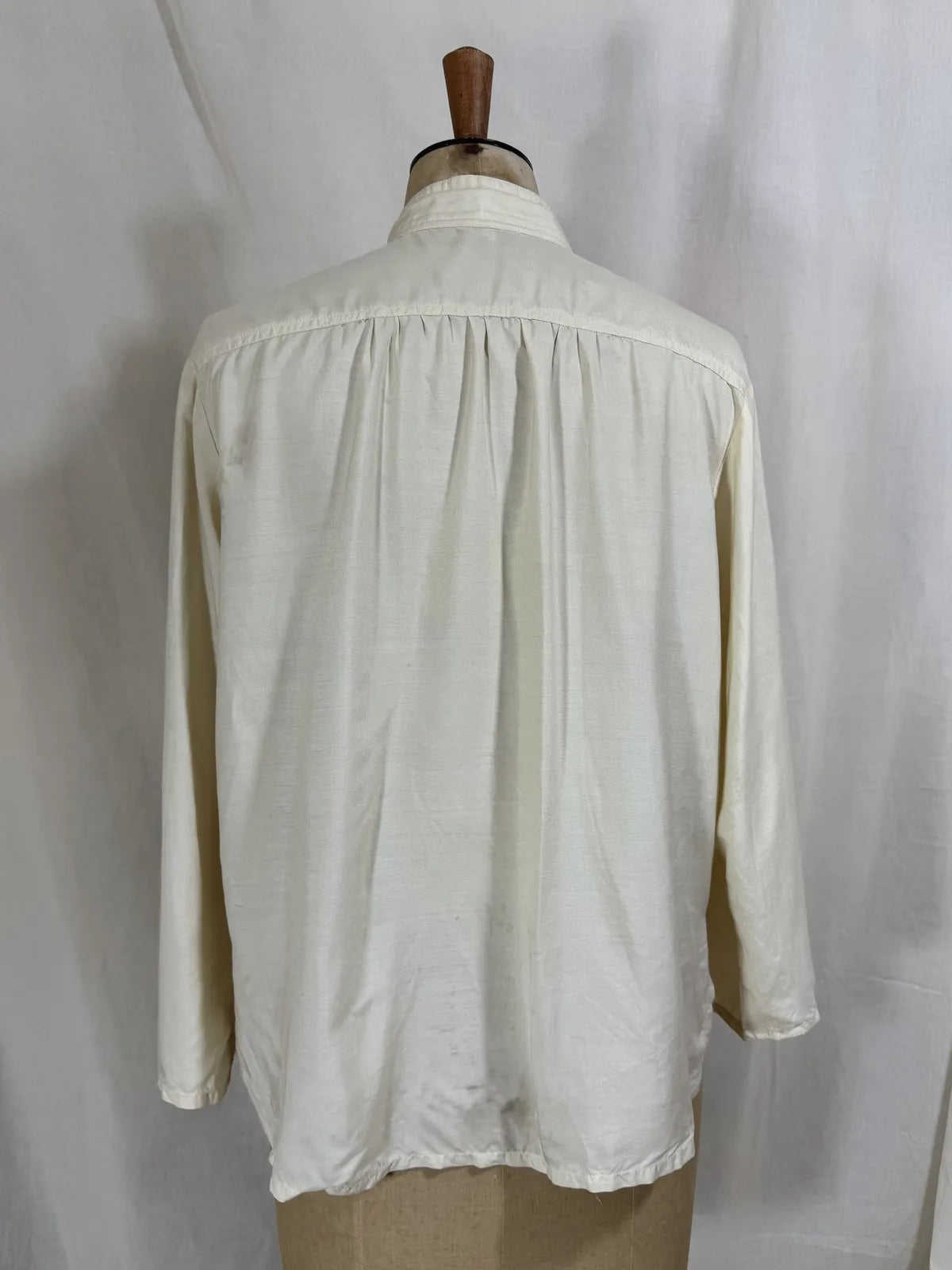 1960 white silk blouse on a mannequin against a white background