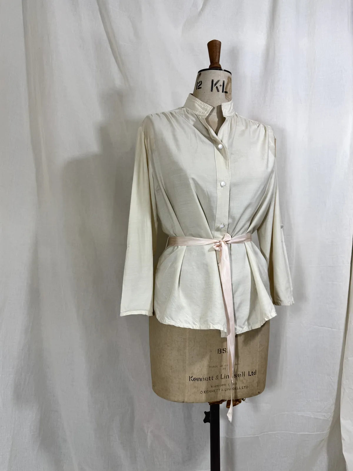 1960 white silk blouse on a mannequin against a white background