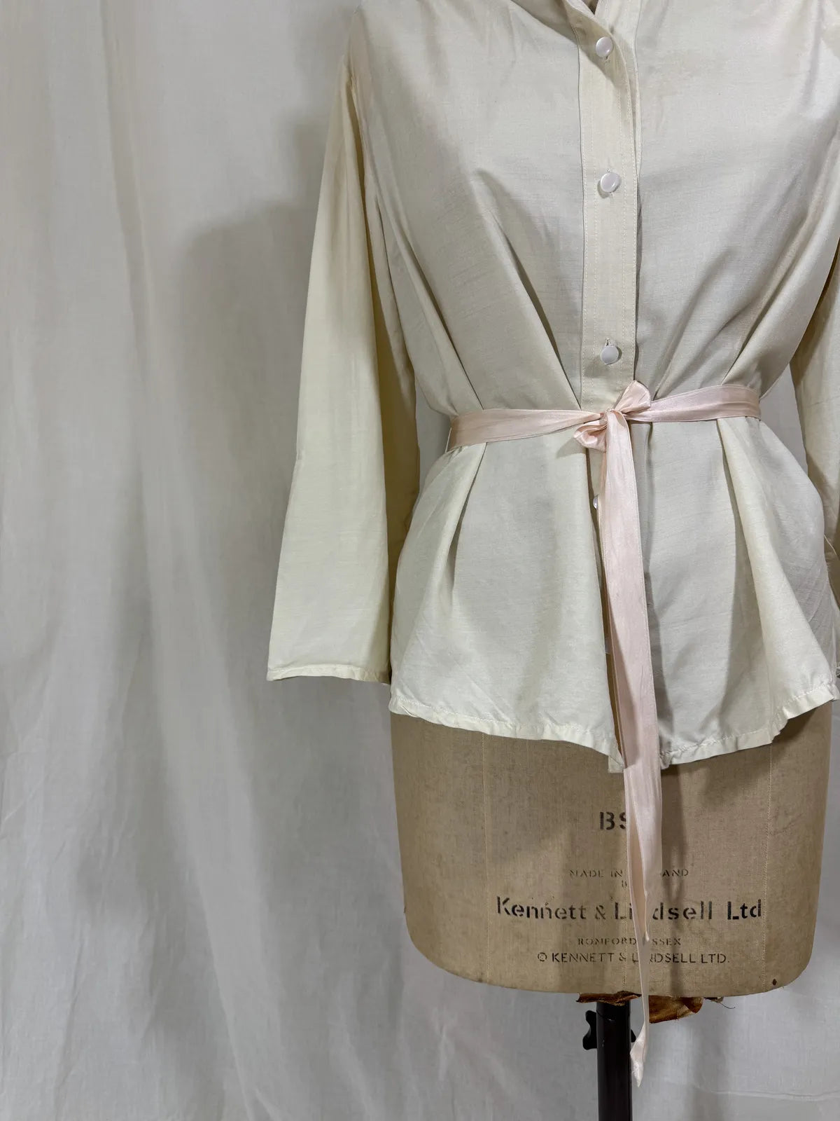 1960 white silk blouse on a mannequin against a white background