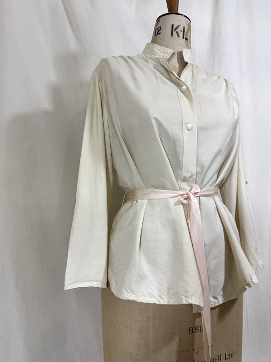 1960 white silk blouse on a mannequin against a white background