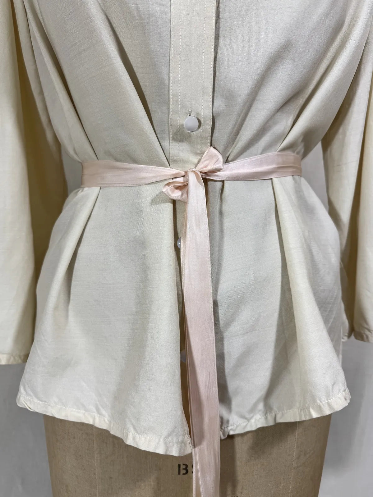 1960 white silk blouse on a mannequin against a white background
