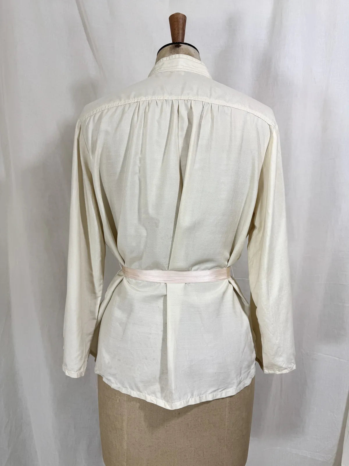 1960 white silk blouse on a mannequin against a white background