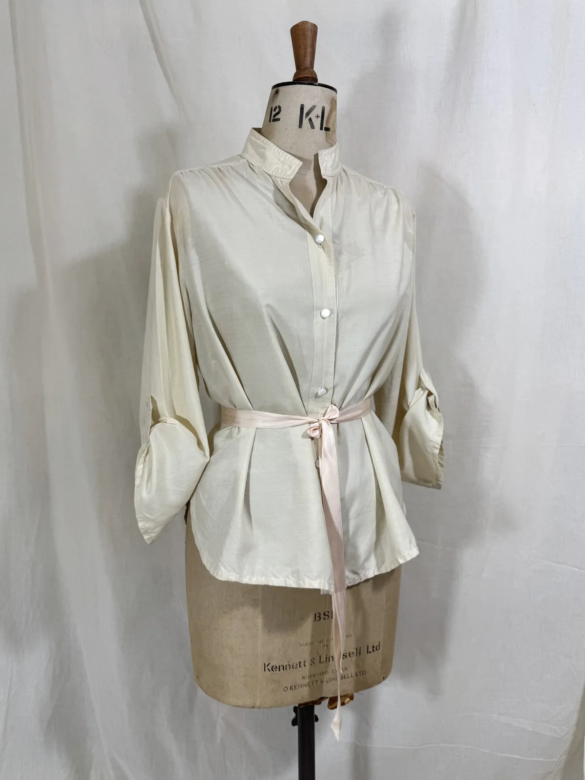 1960 white silk blouse on a mannequin against a white background