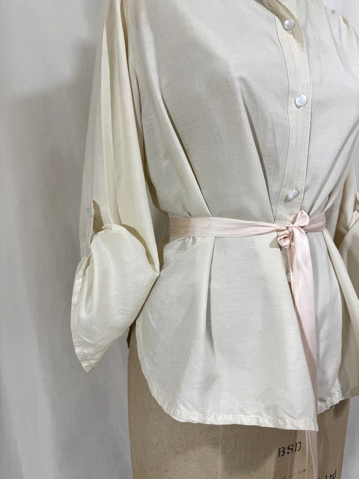 1960 white silk blouse on a mannequin against a white background