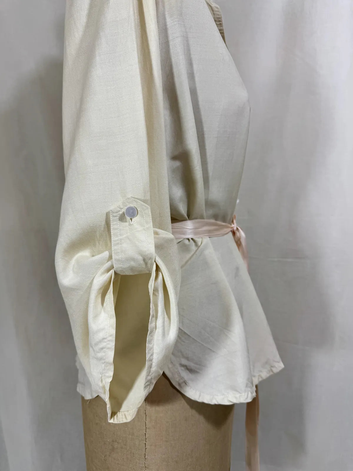 1960 white silk blouse on a mannequin against a white background