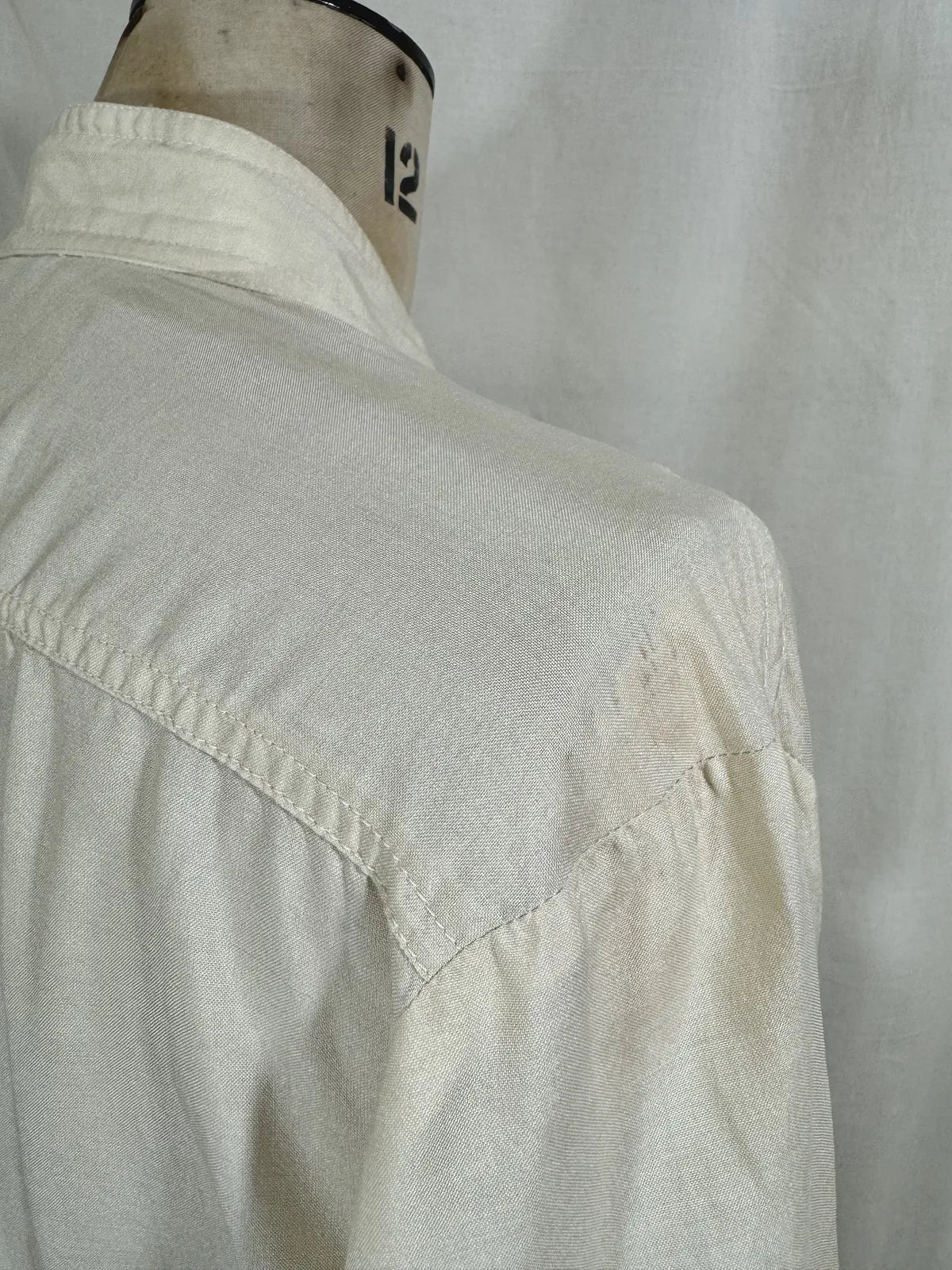 1960 white silk blouse on a mannequin against a white background