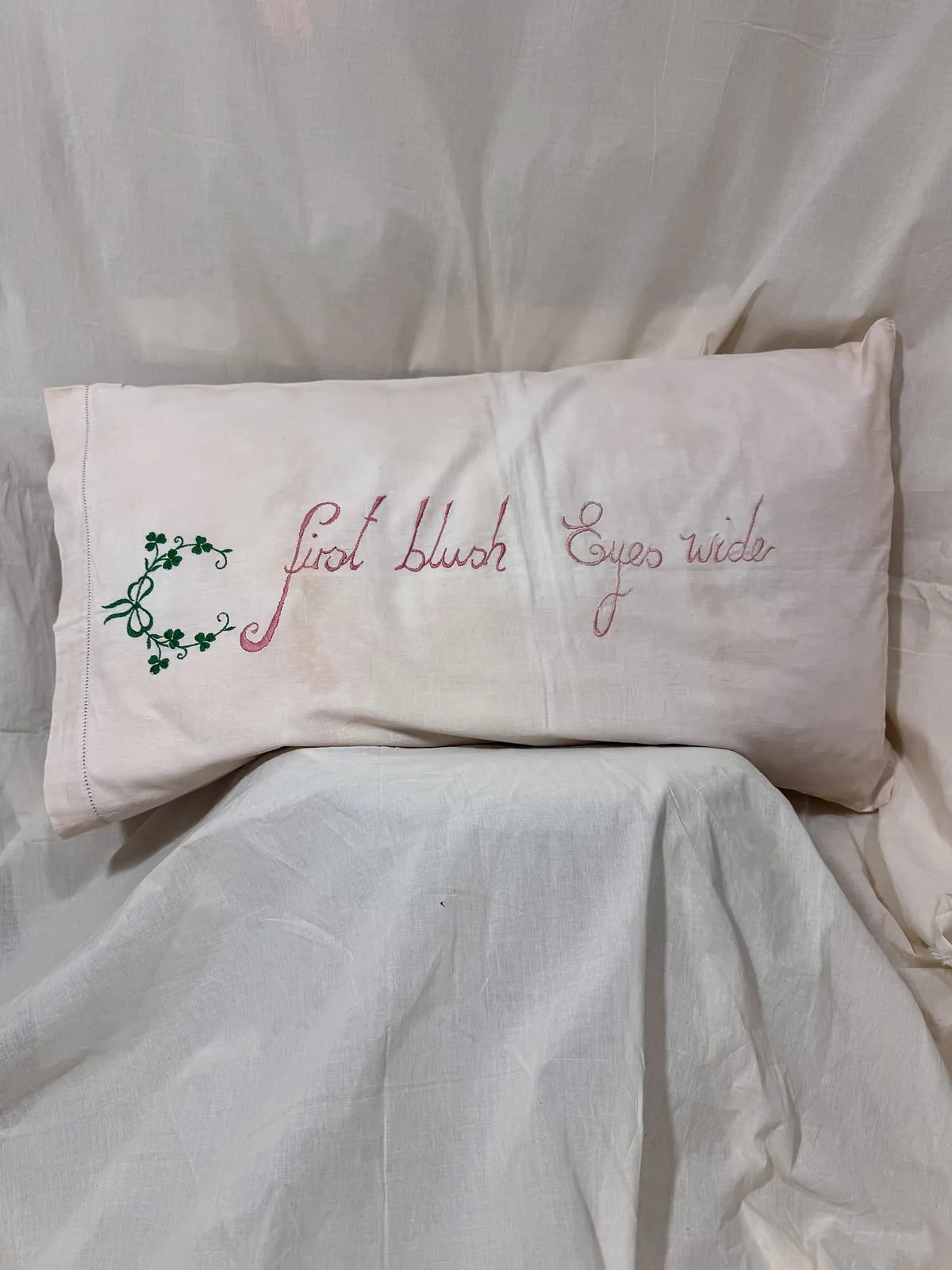 Embroidered pillow with decorative text on a white background