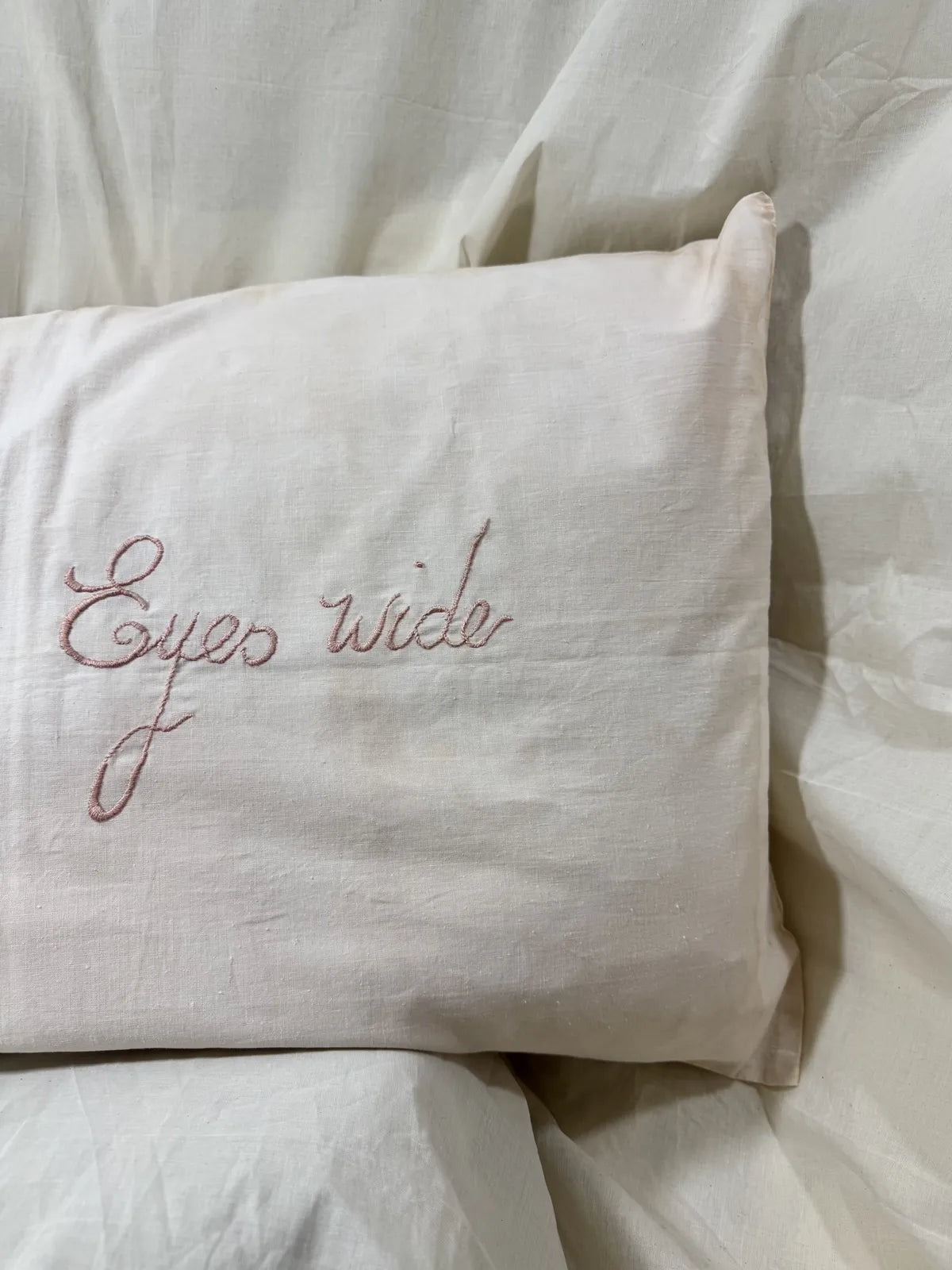 Embroidered pillow with decorative text on a white background