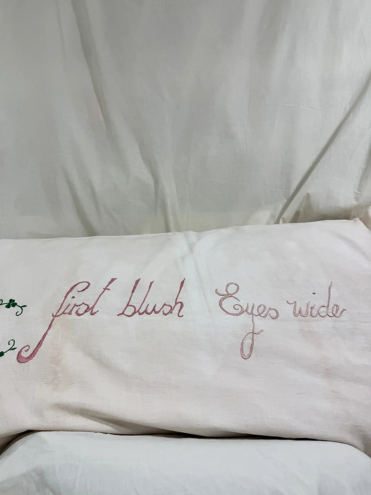 Embroidered pillow with decorative text on a white background