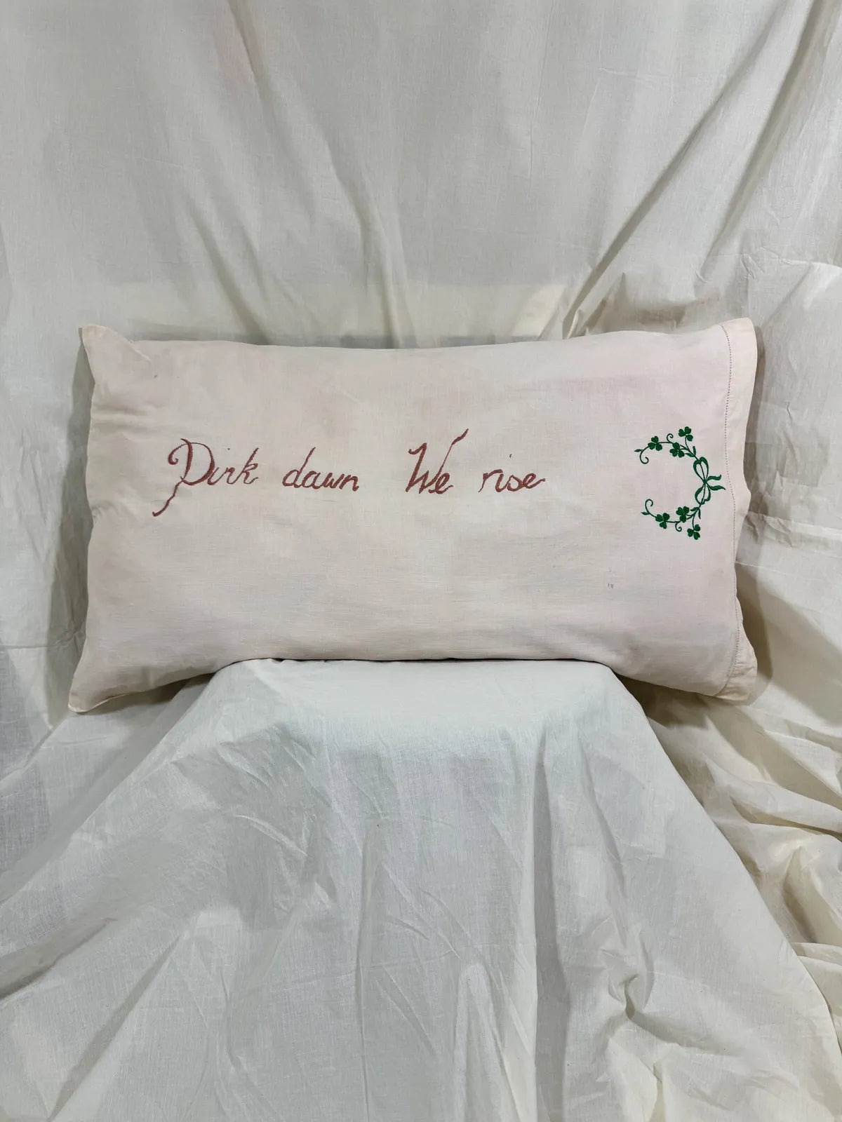 Decorative pillow with embroidered text and design on a bed