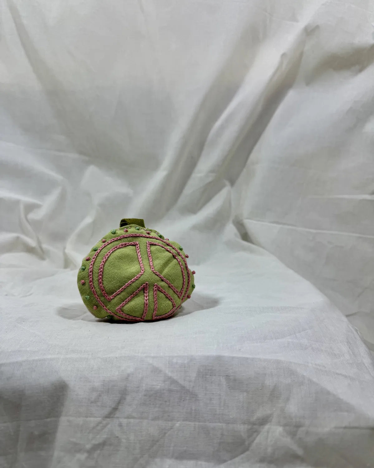 Green textured ball with pink patterns on a white fabric background