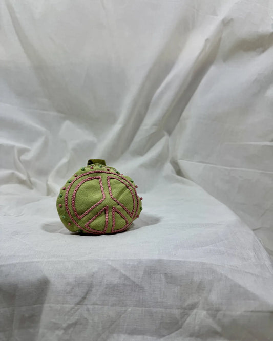 Green textured ball with pink patterns on a white fabric background