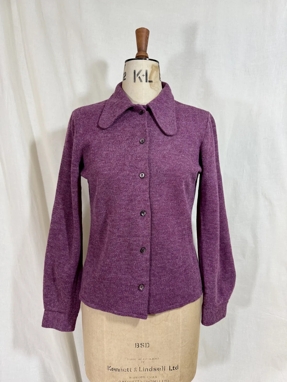 Purple wool cardigan on a mannequin with a white background
