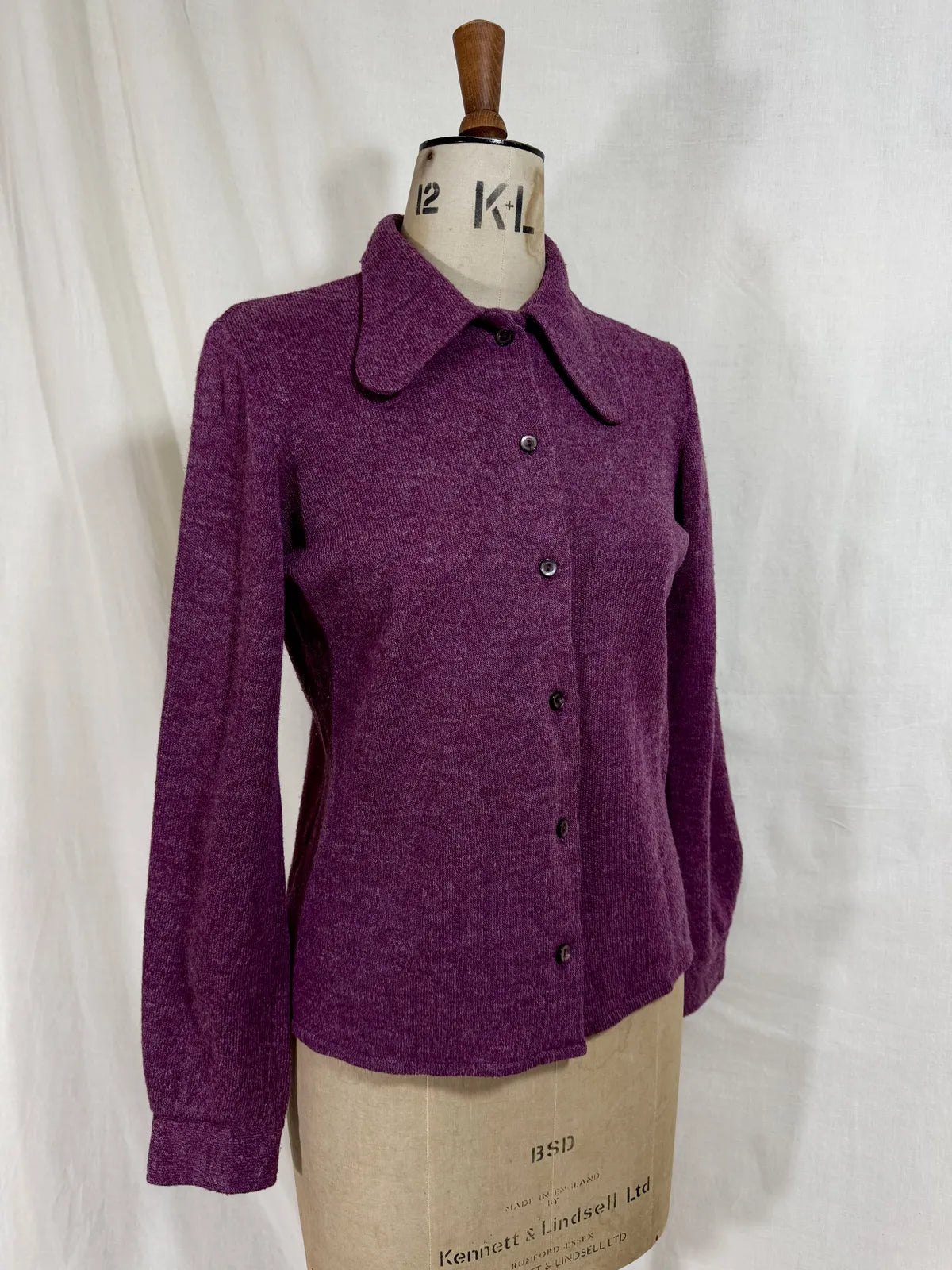 Purple wool cardigan on a mannequin with a white background