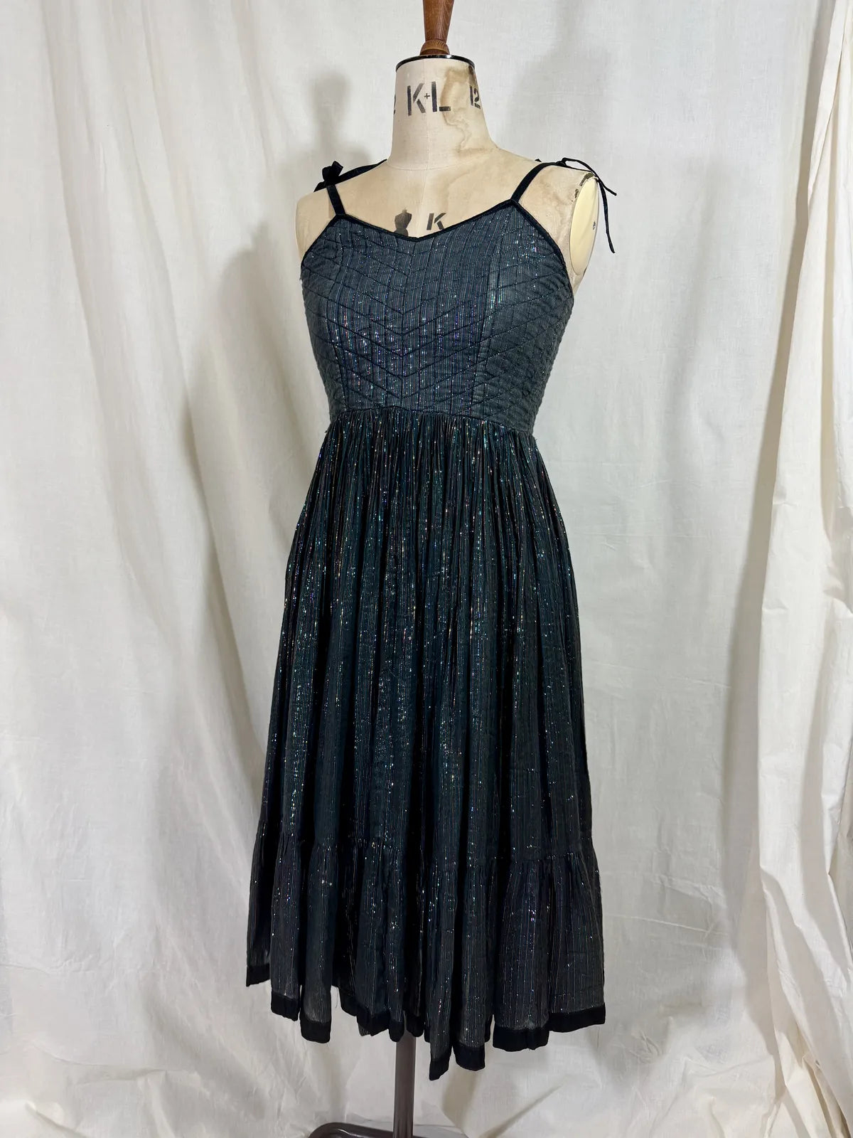 Black metallic cotton gauze dress on a mannequin against a white curtain background