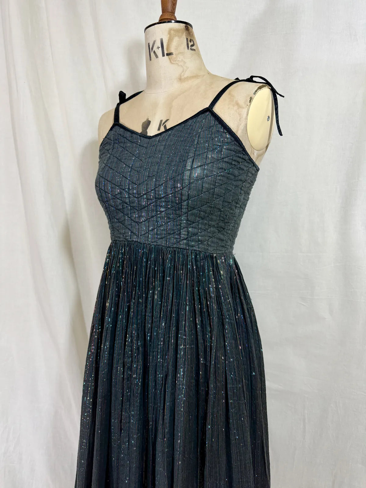Black metallic cotton gauze dress on a mannequin against a white curtain background